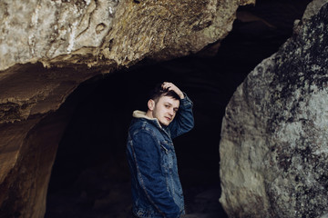 Fototapeta premium Young sad man in a cave in the mountains