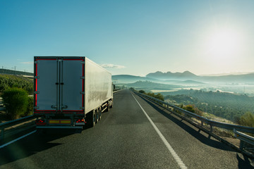 Truck driving on the highway in front of a foggy landscape