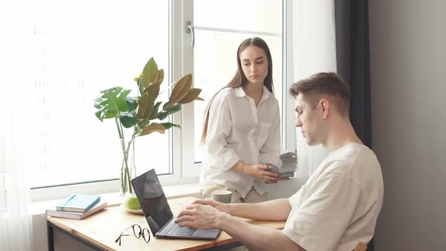 Stay home. Beautiful couple at home. Man work at home, he is in freelance during quarantine coronavirus, he use laptop.