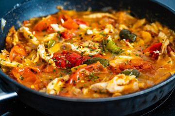 Chicken ragout with tomatoes, pepper and onion in cooking pan