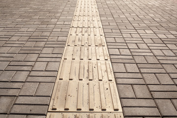 Bright yellow tactile paving for the visually impaired on the sidewalk