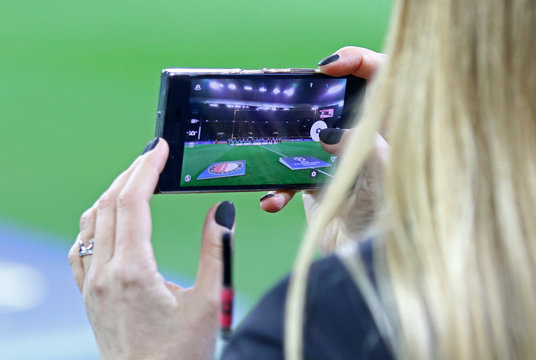 Woman takes a photo of OSK Metalist stadium in Kharkiv on her smartphone before UEFA Champions League game