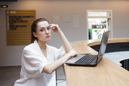 Lifestyle portrait in the interior. A young woman works at a laptop in a coworking,