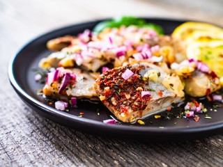 Marinated herrings with lemon and onion on wooden table
