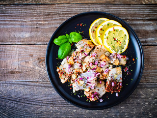 Marinated herrings with lemon and onion on wooden table
