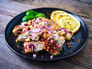 Marinated herrings with lemon and onion on wooden table
