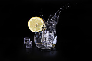 ice water splash with lemon slice isolated on black background