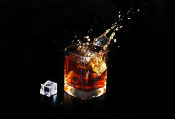 whiskey splash with ice isolated on black background