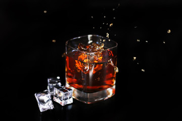 whiskey splash with ice isolated on black background