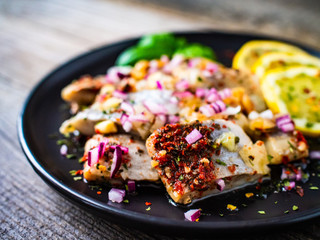 Marinated herrings with lemon and onion on wooden table

