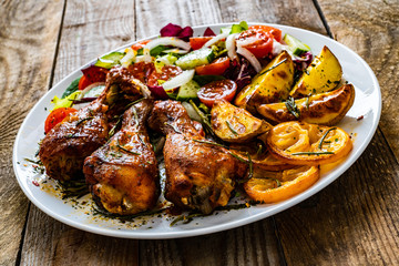 Barbecue chicken drumsticks with vegetables on wooden table