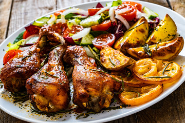 Barbecue chicken drumsticks with vegetables on wooden table