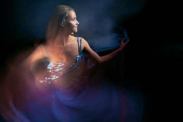 Dancing girl in a blue dress on a blue background, the effect of movement and rotation,