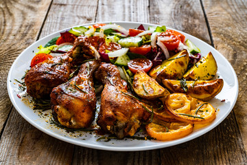 Barbecue chicken drumsticks with vegetables on wooden table