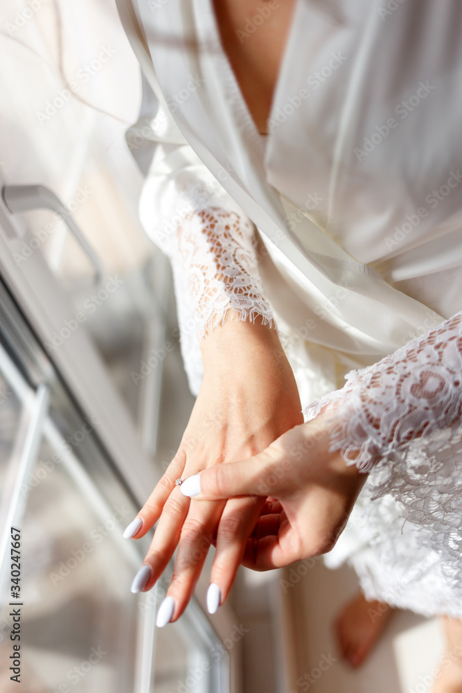 Wall mural A bride in a bathrobe and veil strokes her fingers with a wedding ring. Female fingers with a ring.