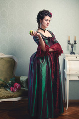 A gorgeous brunette in a 18th century historical dress with an apple in her hand
