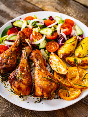 Barbecue chicken drumsticks with vegetables on wooden table