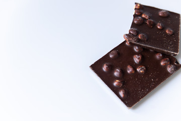 A bar of milk chocolate with hazelnuts on a white background