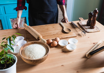 Woman cooking pastries and bread at home looking for recipes on tablet