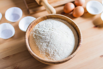 Bowl with flour, eggs, rolling pin and cup papers for making pastries