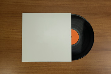 Empty white paper Vinyl disk case and black vinyl with orange tag in a wood background for mockup purposes