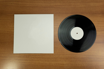 Empty white paper Vinyl disk case and black vinyl with white tag in a wood background for mockup purposes