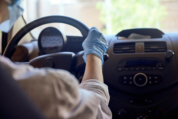 Woman in surgical face mask and gloves driving car