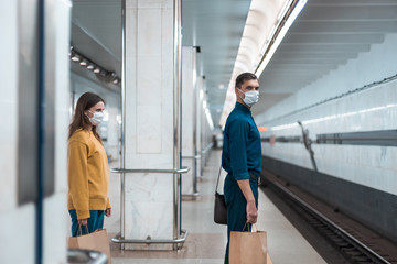 Naklejka na ściany i meble passengers in protective masks waiting for the metro train