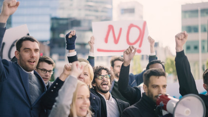 Multicultural Diverse Office Managers and Business People Picketing Outside on a Street. Men and Women Screaming for Justice, Holding a Megaphone, Picket Signs and Posters. Economic Crisis Strike.