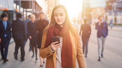 Young Casually Dressed Female is Using a Smartphone on a Street. Business People and Office...