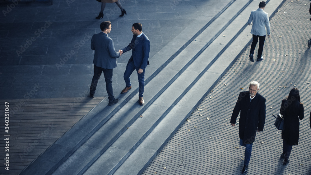 Wall mural Office Managers and Business People Commute to Work in the Morning or from Office on a Sunny Day on Foot. Pedestrians are Dressed Smartly. Two Businessmen Shake Hands. Shot from Above.