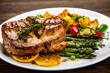 Barbecue beef steak fried potatoes and vegetables on wooden table