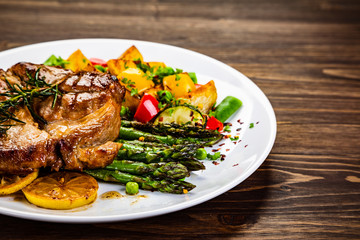 Barbecue beef steak fried potatoes and vegetables on wooden table