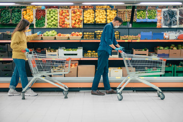 man and a woman with shopping carts in a supermarket during the quarantine period.