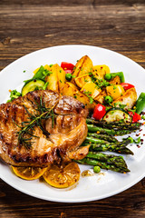 Barbecue beef steak fried potatoes and vegetables on wooden table
