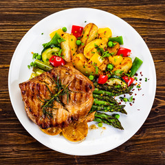 Barbecue beef steak fried potatoes and vegetables on wooden table