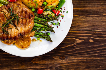 Barbecue beef steak fried potatoes and vegetables on wooden table