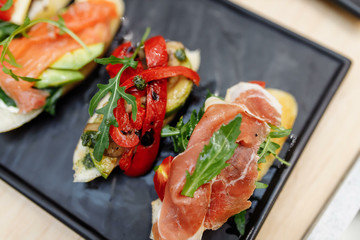 Tasty italian appetizer bruschettes with tomatoes anchovies prosciutto, mozarella, shrimps and seafood