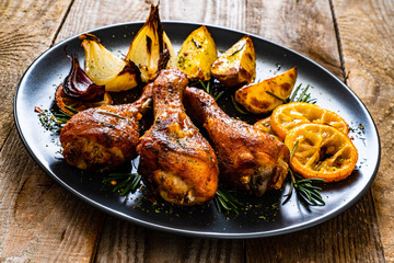 Barbecue chicken drumsticks with vegetables on wooden table