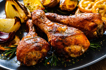 Barbecue chicken drumsticks with vegetables on wooden table