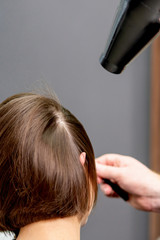 Fototapeta premium Hairstylist dries hair of woman.