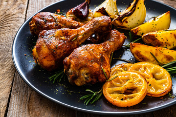 Barbecue chicken drumsticks with vegetables on wooden table