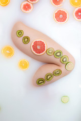 Female foot in a bath with fruit and milk