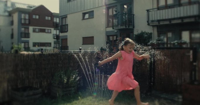 Uśmiechnięta dziewczynka biega w ogrodzie i świetnie się bawi.
