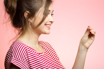 young happy woman with checking result of a one-time pregnancy test, family planning, motherhood concept on pink studio background