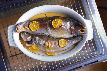 Flat lay two fishes with rosemary and lemon in white plate cooked home