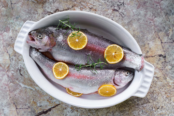 Flat lay two fresh fishes with rosemary and lemon in white plate cooking at home