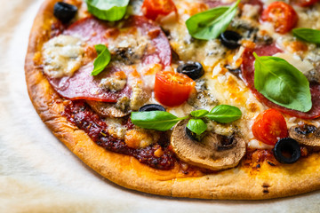 Pizza with pepperoni gorgonzola and champignons  on baking paper 