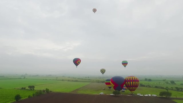Aerial view of hot air balloons floating over fields.