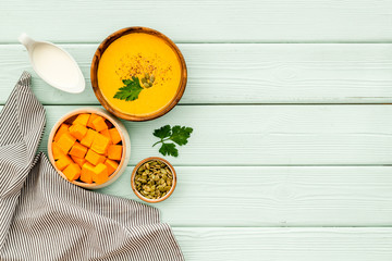 Pumpkin cream soup on green wooden table top view. Autumn meal. Copy space